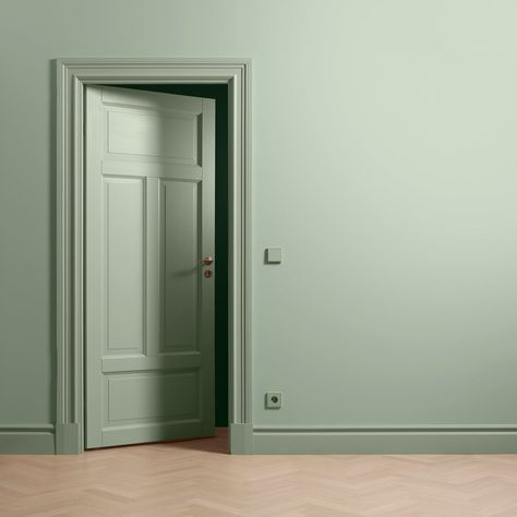 an open door in a green room with parquet flooring and walls painted light green