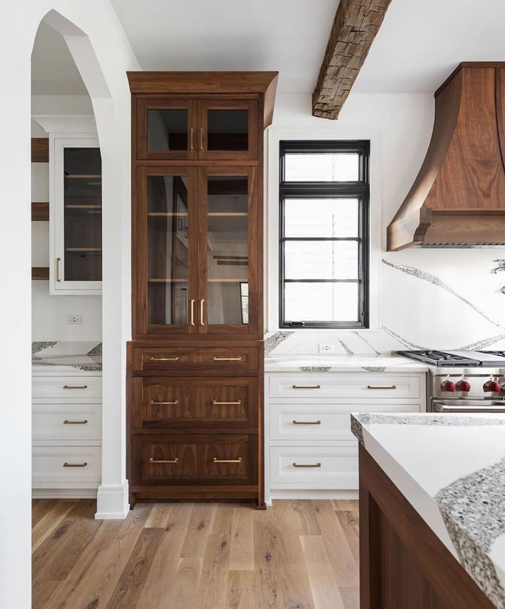 an empty kitchen with wooden cabinets and marble counter tops, along with hardwood flooring