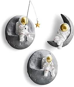 three ornaments depicting an astronaut sitting on the moon