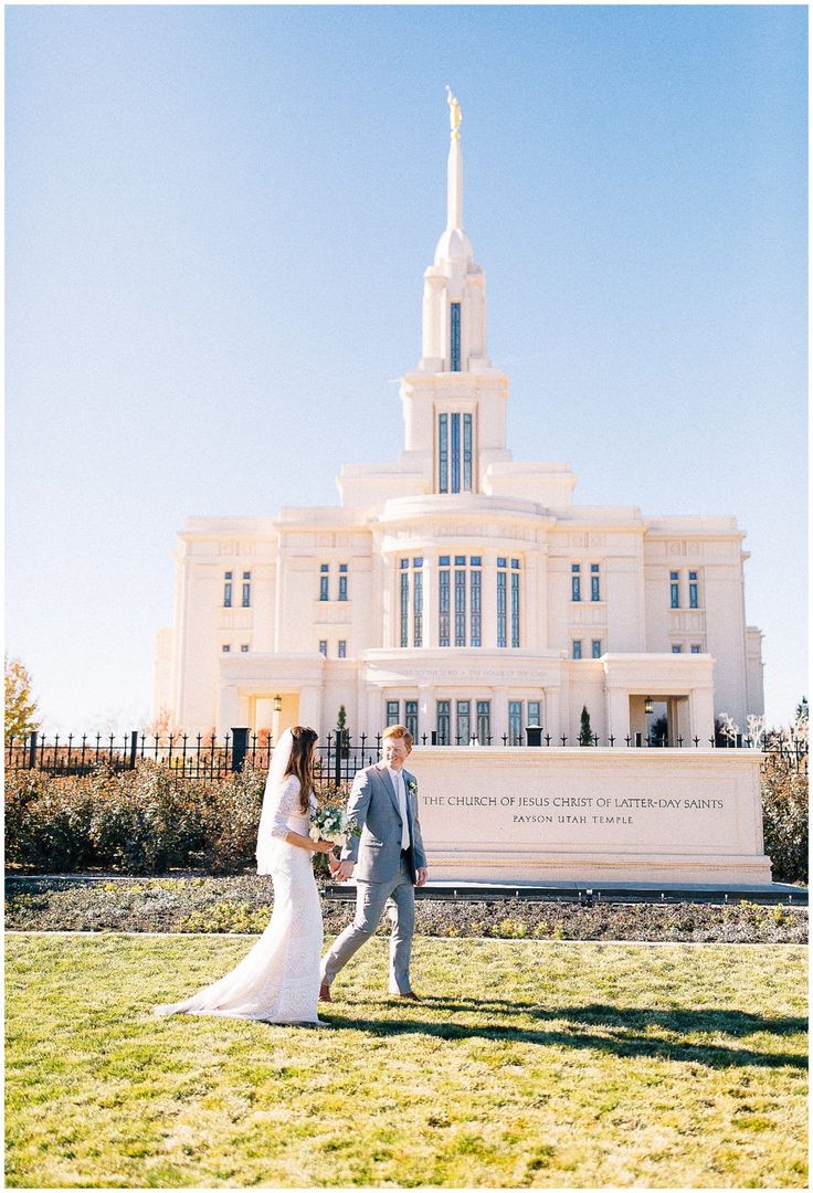 a bride and groom standing in front of the mormon temple on their wedding day, holding hands