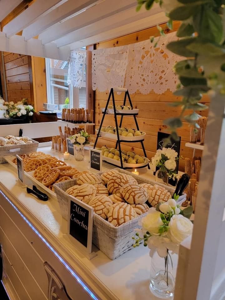 a buffet with breads, pastries and flowers on the counter at a wedding