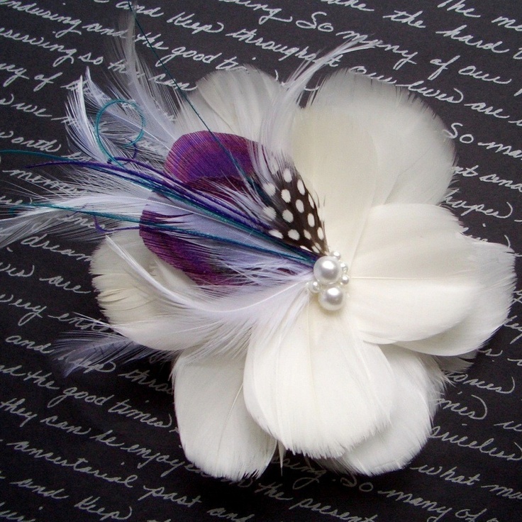 a white flower with purple and blue feathers on it's center, sitting on a black background