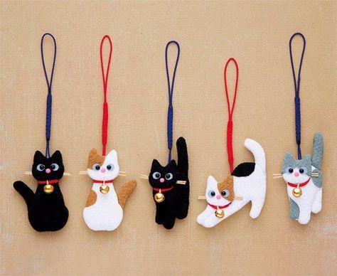 five different cat ornaments hanging from strings on a wall in the shape of an ornament