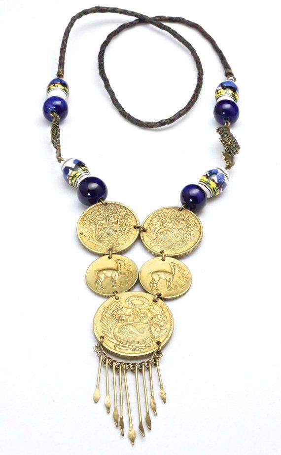 Vintage Peruvian Coin Tribal Beaded Necklace-Statement necklace with 5 jump ring connected Peruvian coins-Hanging from the bottom large coin are brass pins with flattened, pointed ends-Painted scene ceramic beads and dark blue glass beads are connected with 2 brass metal God figural beads-A simple braided leather strand is connected to the beading a coin section-No clasp, simply pull over the head-Length of beaded section approx 9.5"-Drop is about 4.5" including the length of the pins-Total wear Bohemian Brass Coin Necklace, Adjustable Brass Coin Necklace, Festival Coin Pendant Necklace In Medallion Shape, Traditional Brass Coin Necklace, Handmade Amulet Coin Necklace, Traditional Handmade Medallion Coin Necklace, Bohemian Metal Coin Necklace, Bohemian Brass Medallion Coin Necklace, Handmade Antique Coin Necklace For Festival