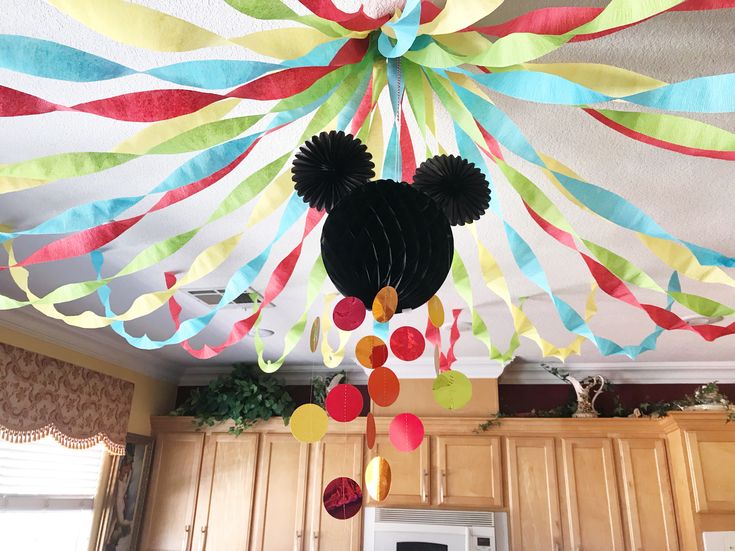 a mickey mouse party decoration hanging from the ceiling with streamers and paper streamers