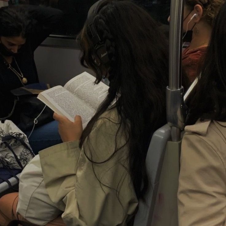 two women sitting on a bus reading books