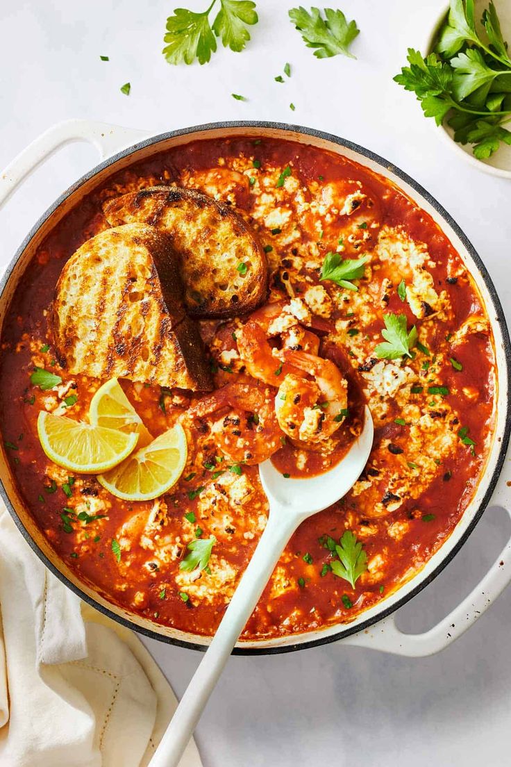 a large pot filled with shrimp and tomato sauce, garnished with parsley