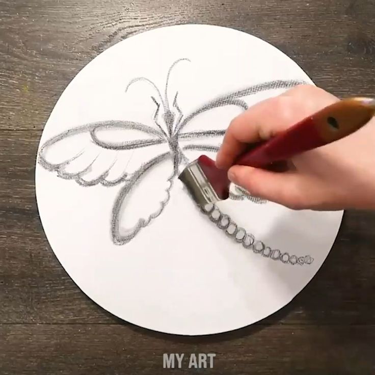 someone is drawing a butterfly on a white paper