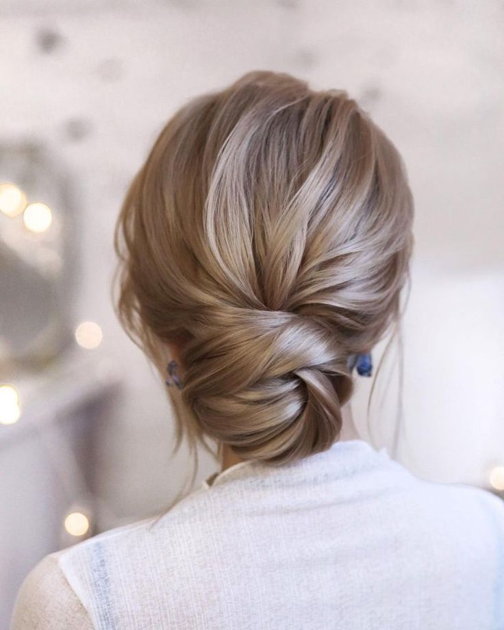 a woman with blonde hair styled into a low bun in front of a christmas tree