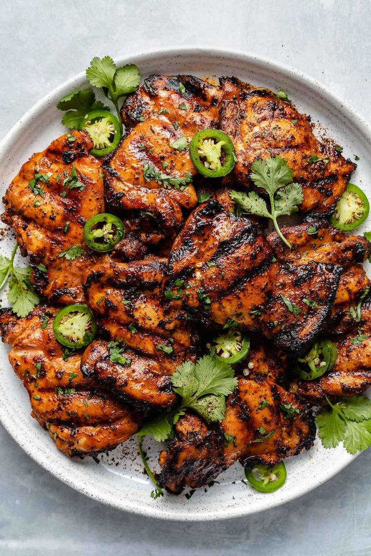 grilled chicken with green peppers and cilantro on a white plate, top view