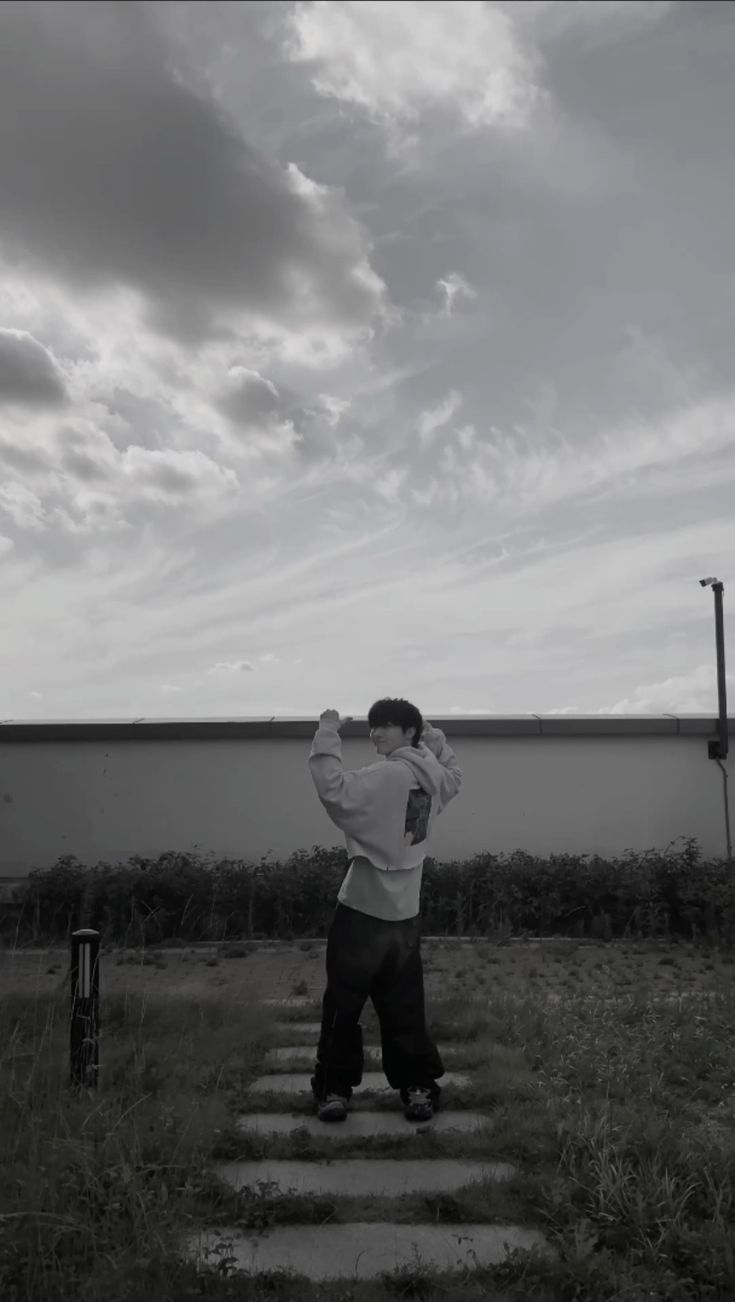 a man is standing on some steps with his hands behind his head and looking at the sky