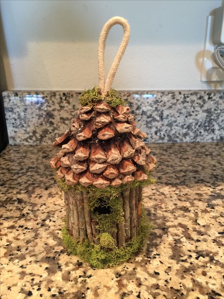 a small house made out of wood sticks and moss on top of a granite counter