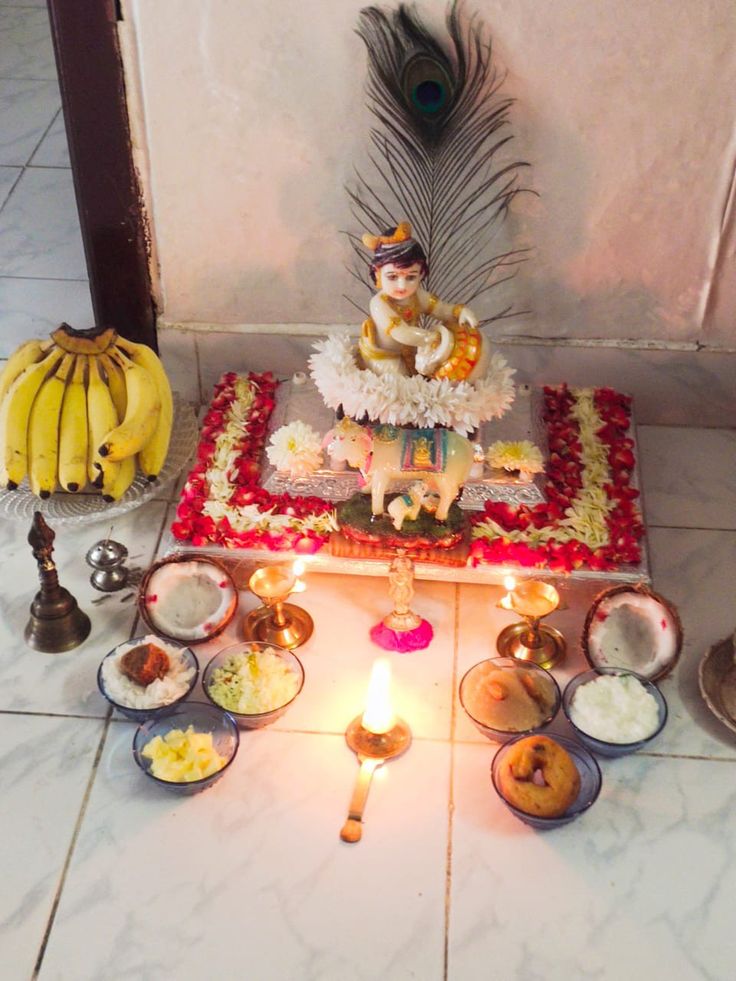 there is a small statue on the floor with food and candles in front of it