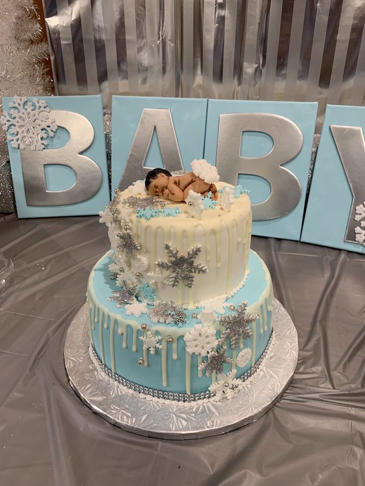 a baby is laying on top of a blue and white cake with snowflakes