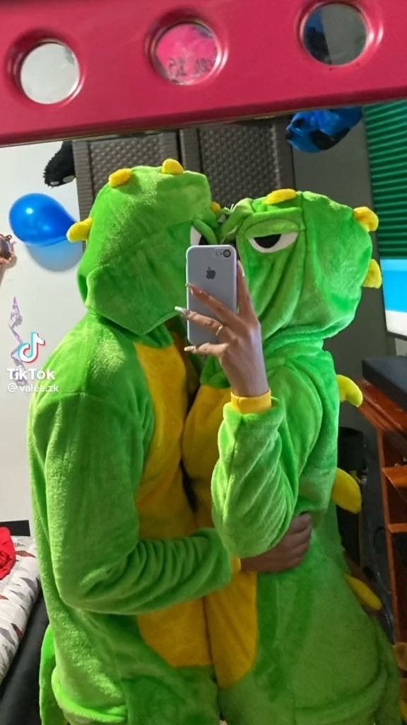 a person in a frog costume taking a selfie with a cell phone while looking at the mirror