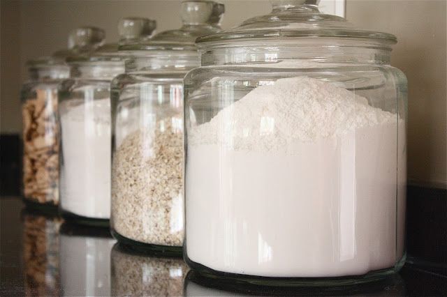 there are many jars with different types of food on the counter top, and one is filled with rice