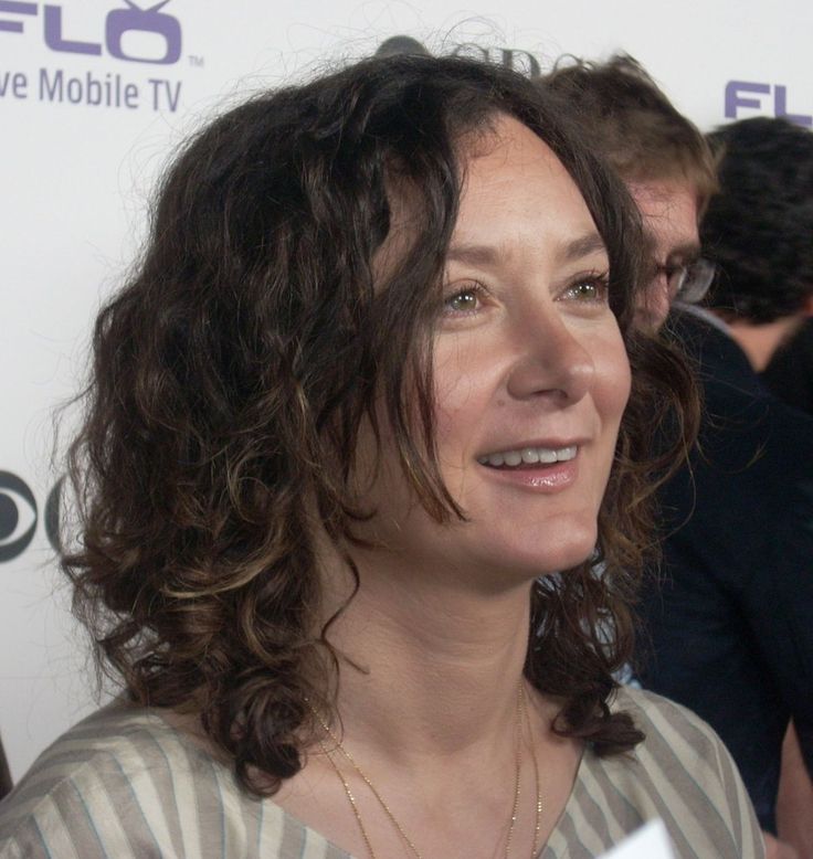 a woman with curly hair is smiling at the camera while standing next to other people