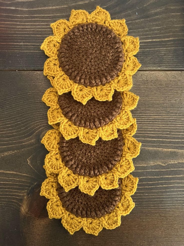 three crocheted sunflower coasters sitting on top of a wooden table