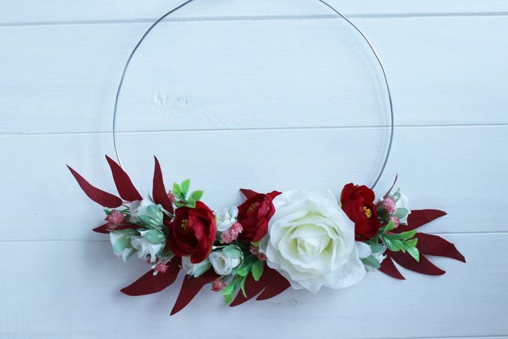 a white and red wreath with flowers on it