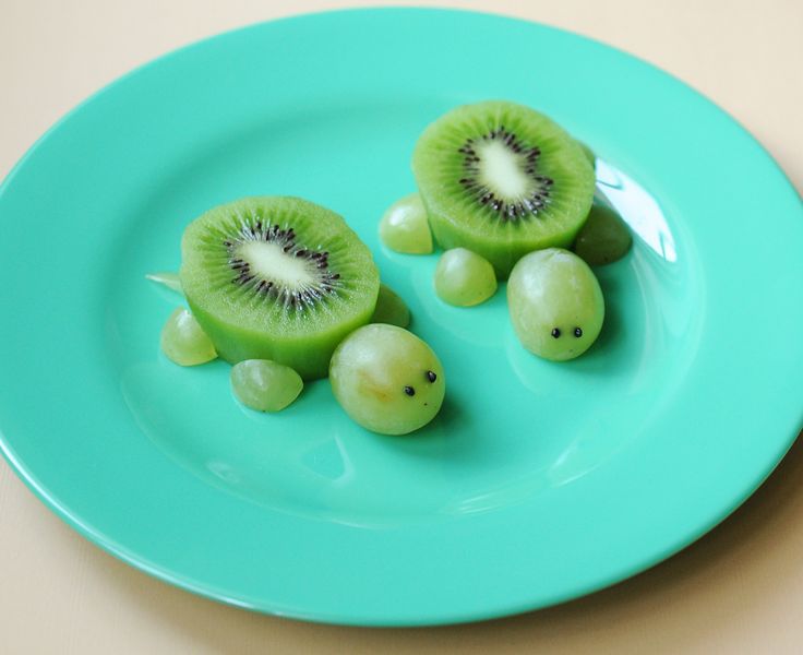 two pieces of kiwi fruit on a plate with the words, brincar com comida faz bem