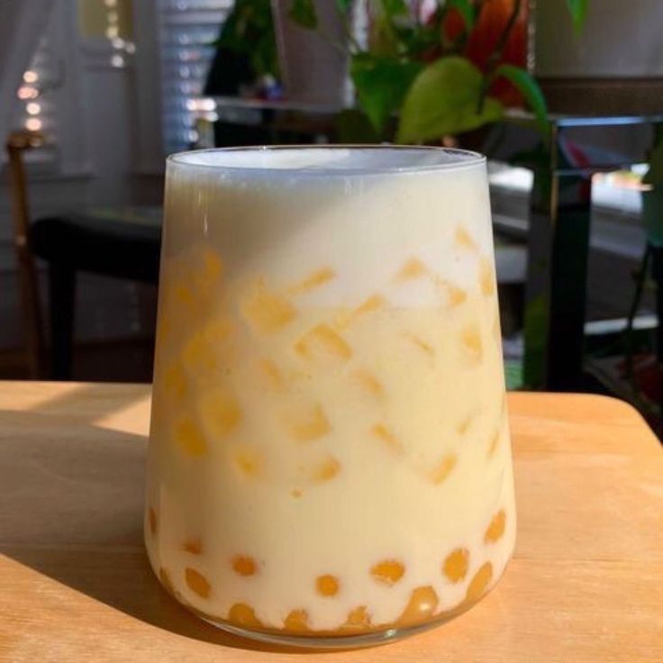 a glass filled with milk sitting on top of a wooden table