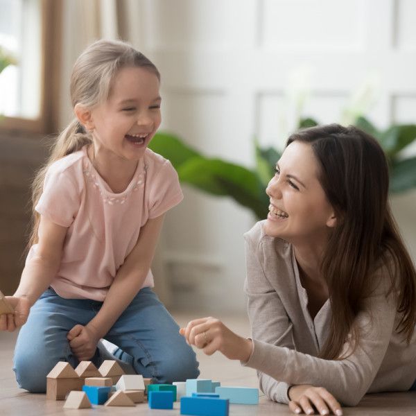 a mother and daughter playing with blocks on the floor