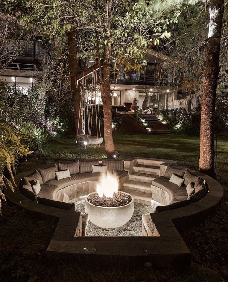 an outdoor fire pit surrounded by trees at night