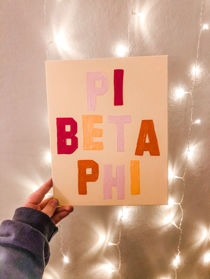 a person holding up a piece of paper with the words pi, beta, phi on it