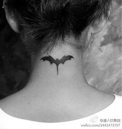 black and white photo of a woman's neck with a bat tattoo on it