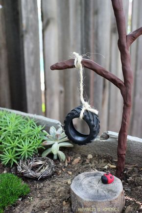 an old tire hanging from a tree branch in a potted planter filled with succulents