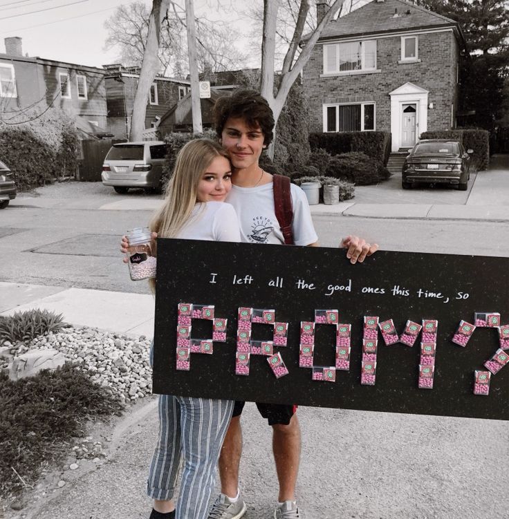 two people holding up a sign that says prom