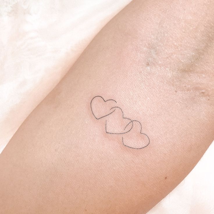 a small tattoo on the arm of a woman with two hearts in it's center