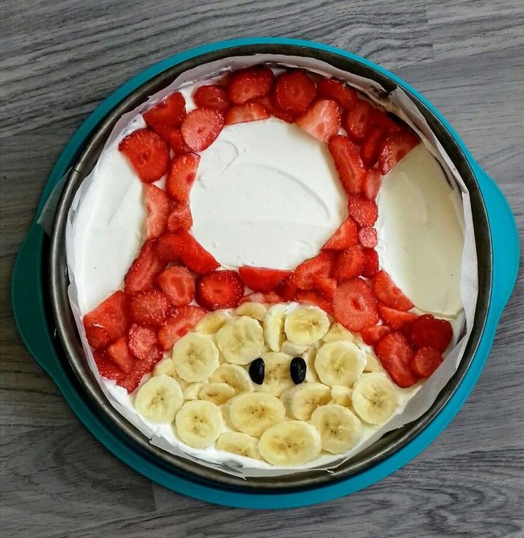 there is a bowl with fruit in it on the table, including bananas and strawberries