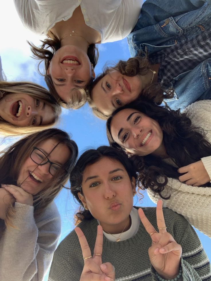 a group of young women standing in a circle making the peace sign with their fingers