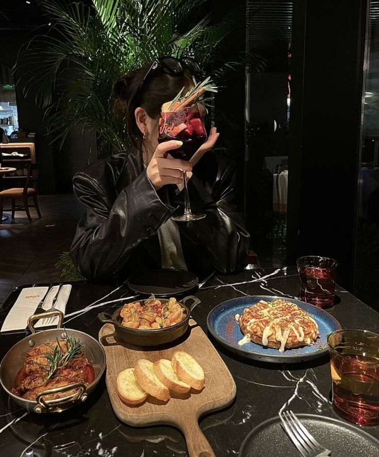 a woman sitting at a table with food and drinks