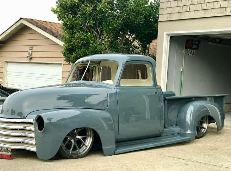 an old blue truck parked in front of a garage