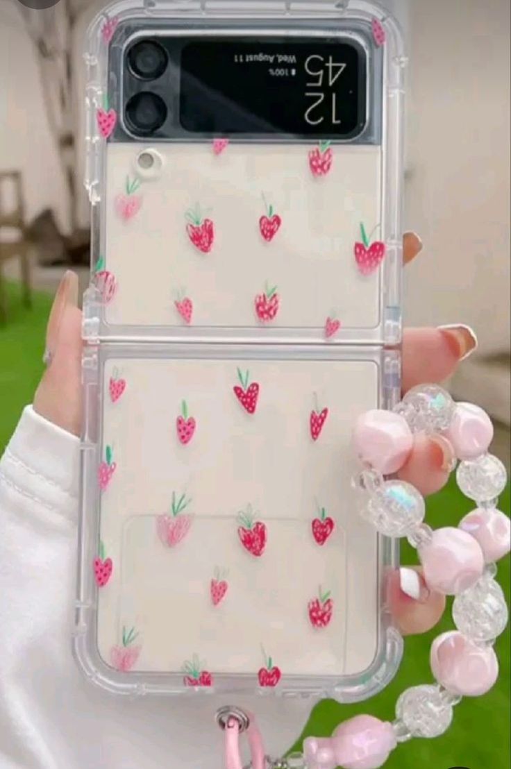 a person holding up a phone case with strawberrys on it