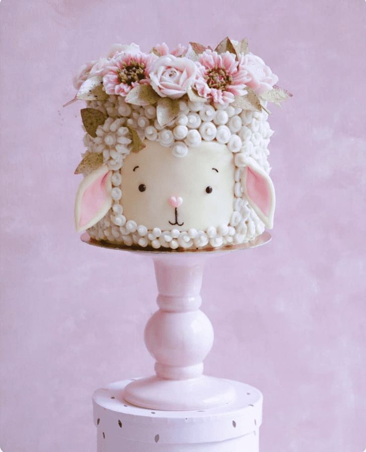 a cake shaped like a sheep with flowers on it's head sitting on top of a table