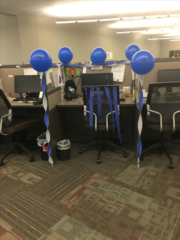 an office cubicle decorated with blue balloons and streamers