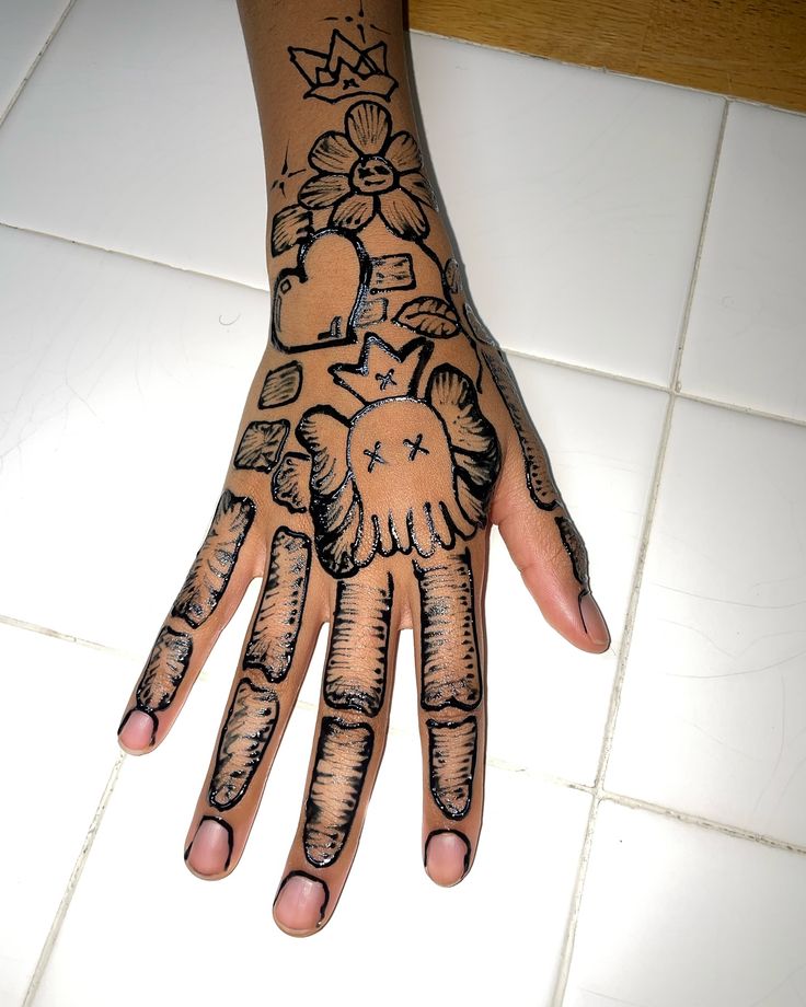 a person's hand with tattoos on it sitting on a tile floor next to a tiled floor