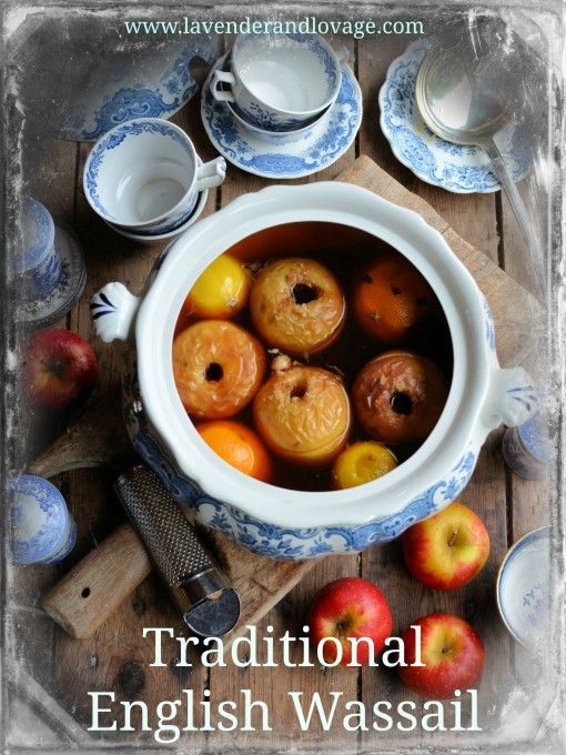 a bowl filled with apples sitting on top of a wooden table next to cups and saucers