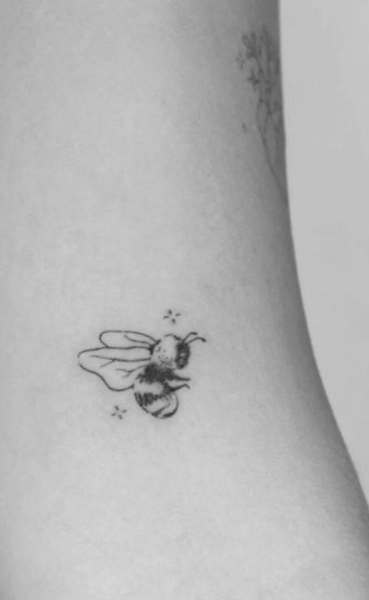 a black and white photo of a bee on the back of a woman's stomach