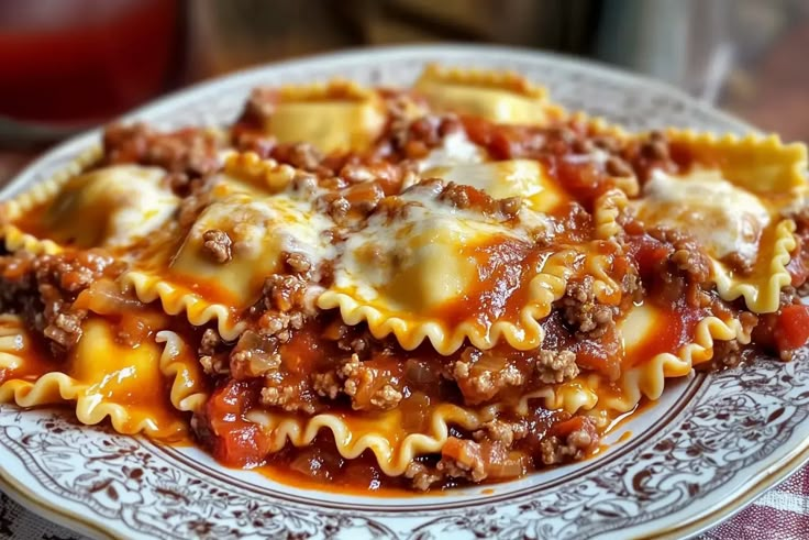 a white plate topped with lasagna shells covered in sauce and cheese on top of a checkered table cloth