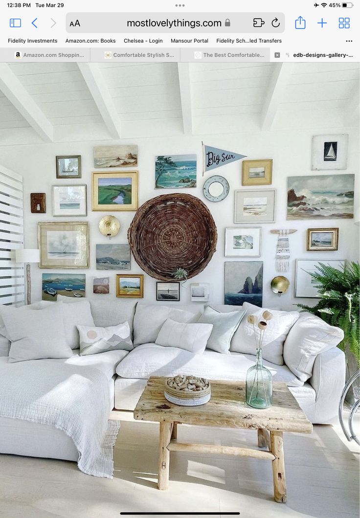 a living room filled with white furniture and pictures on the wall above it's coffee table