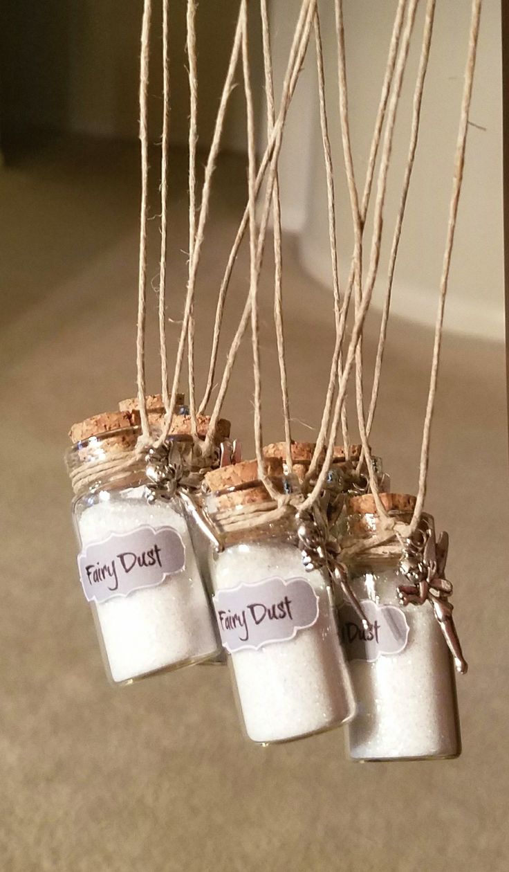 four jars are hanging from the ceiling with twine strings attached to them that say, fairy dust