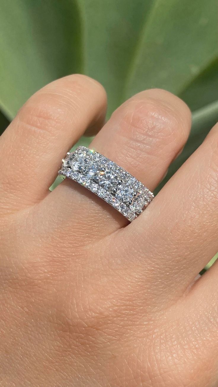 a woman's hand with a wedding ring on it and a plant in the background