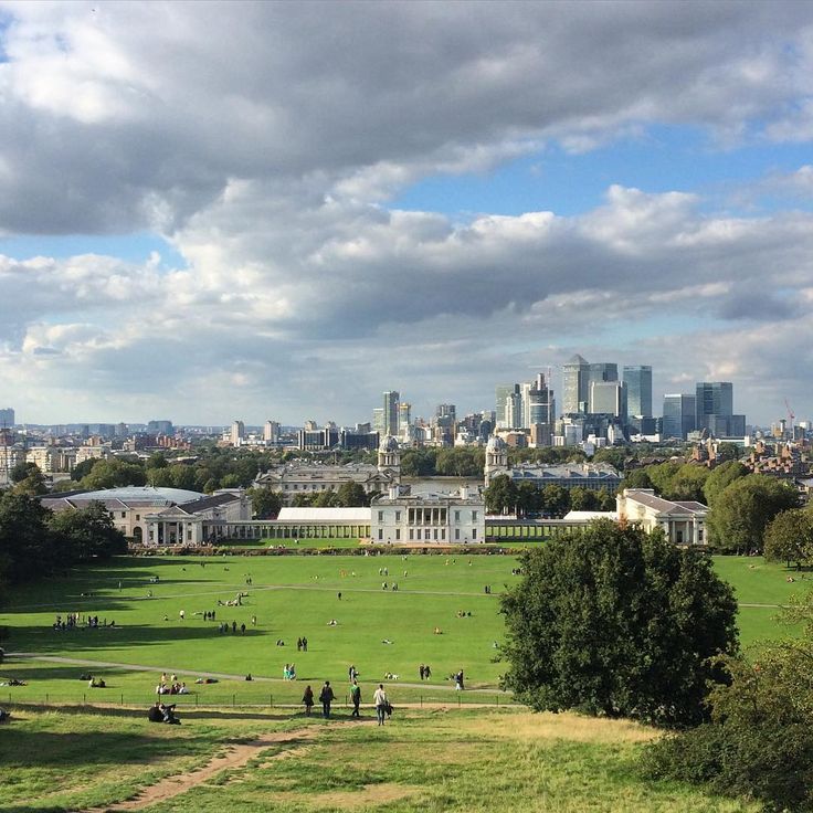 the city skyline is seen in this view from across the park, with many people walking around