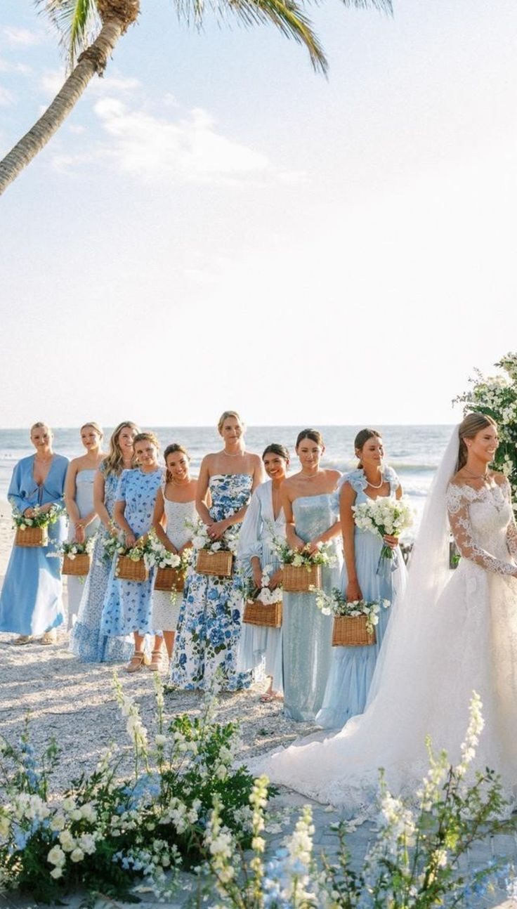 the bride and groom are standing on the beach with their bridal party in blue dresses