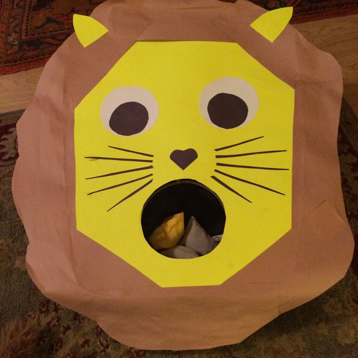 a paper bag with a lion face cut out on the front and side, sitting on top of a rug