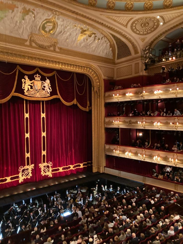 an auditorium filled with lots of people and red curtains